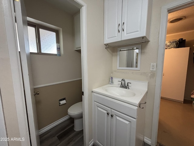 bathroom with baseboards, vanity, toilet, and wood finished floors