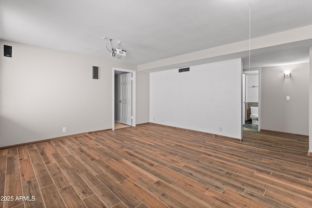 unfurnished living room with visible vents, baseboards, and wood finished floors