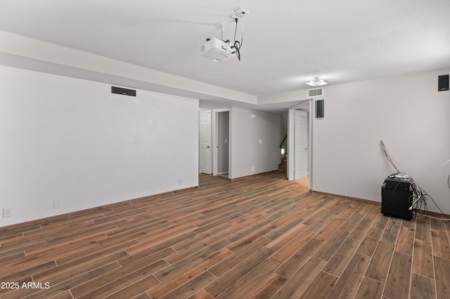 finished below grade area with wood finished floors, visible vents, and stairs