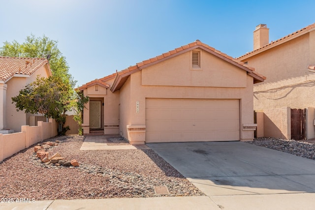 view of front of property with a garage, a tile roof, fence, concrete driveway, and stucco siding
