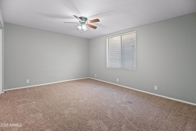 carpeted spare room with baseboards and a ceiling fan