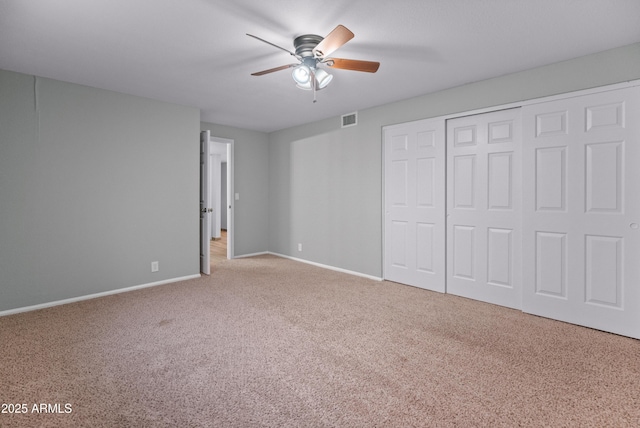 unfurnished bedroom with a closet, baseboards, a ceiling fan, visible vents, and carpet
