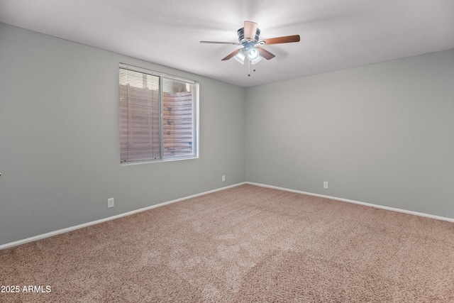 carpeted spare room featuring baseboards and a ceiling fan