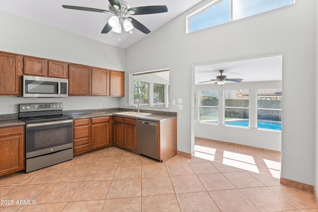 kitchen featuring dark countertops, high vaulted ceiling, appliances with stainless steel finishes, and ceiling fan