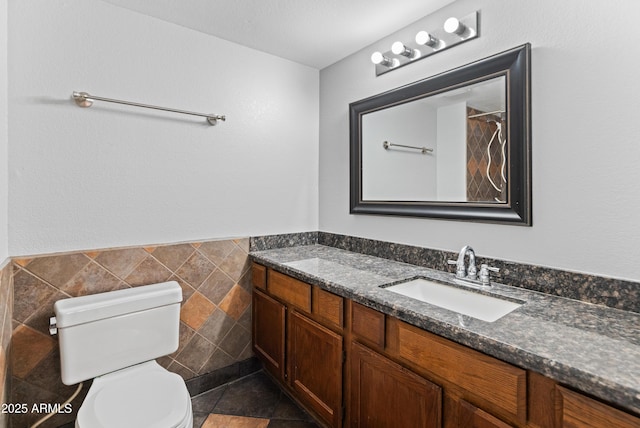 bathroom featuring vanity, tile walls, a wainscoted wall, and toilet