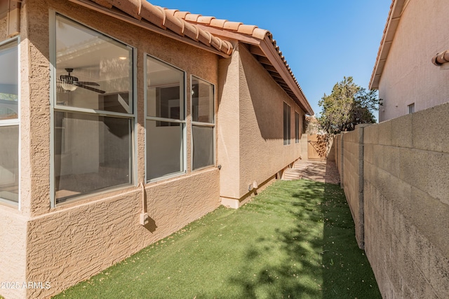 view of side of property featuring a yard, fence, and stucco siding