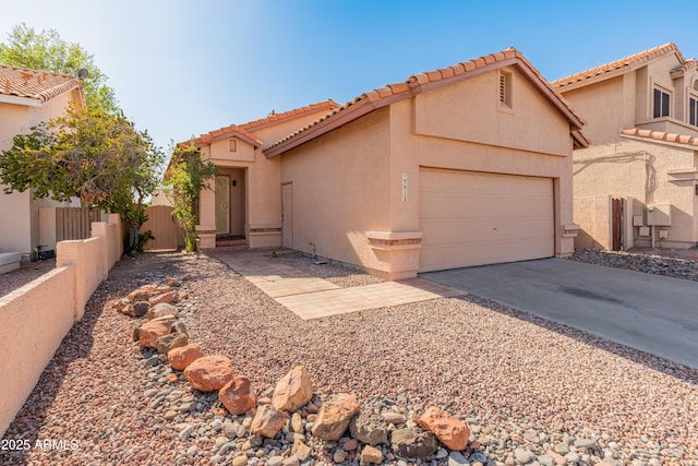 view of front of house with an attached garage, a tile roof, fence, stucco siding, and driveway