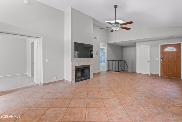 unfurnished living room with high vaulted ceiling, ceiling fan, a fireplace, light tile patterned floors, and visible vents