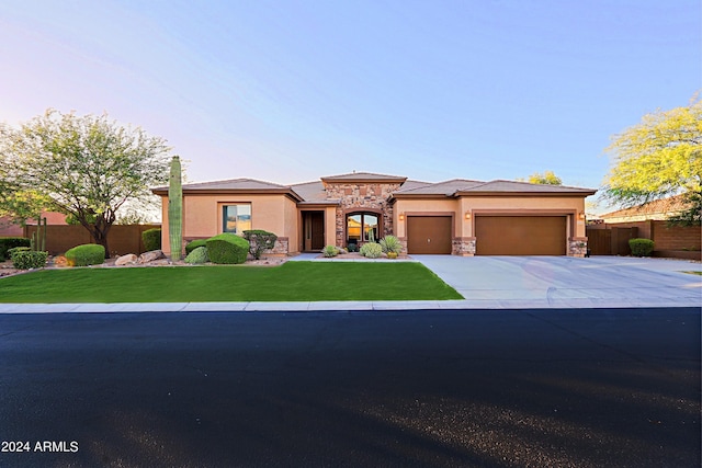prairie-style house with stucco siding, stone siding, an attached garage, and fence