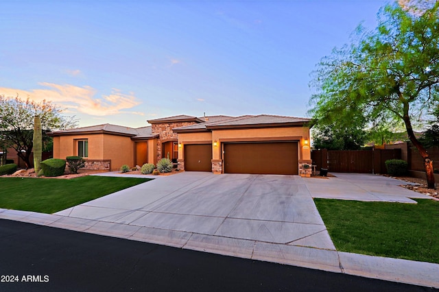 prairie-style house with a front lawn, an attached garage, fence, and stucco siding