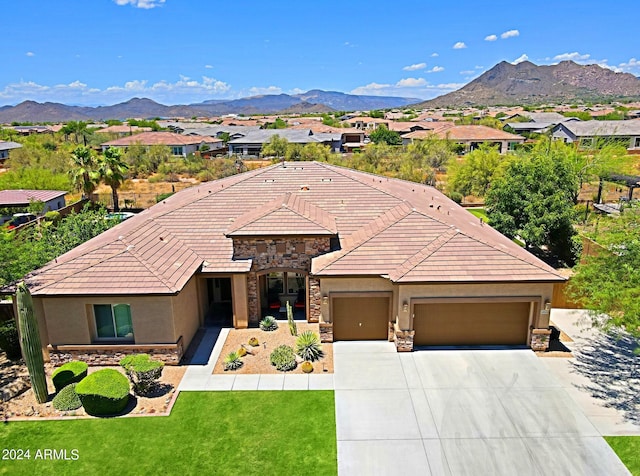 view of front of property featuring stucco siding, stone siding, an attached garage, and a mountain view