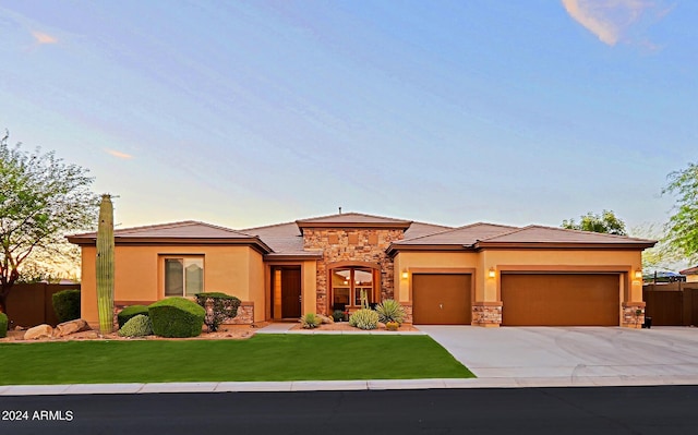 prairie-style house featuring a garage, stone siding, concrete driveway, and stucco siding