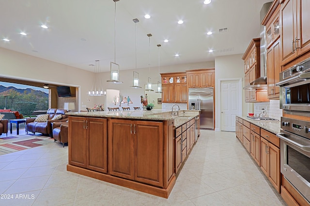 kitchen featuring a spacious island, visible vents, open floor plan, appliances with stainless steel finishes, and brown cabinetry