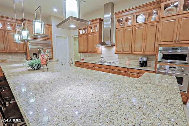 kitchen featuring light stone countertops, stainless steel appliances, a kitchen bar, wall chimney exhaust hood, and backsplash