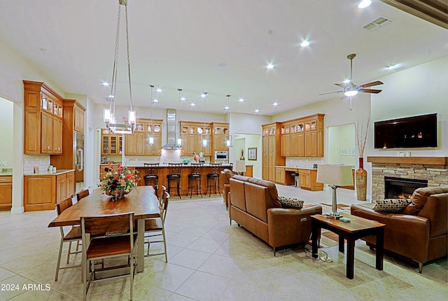 living room featuring a stone fireplace, light tile patterned floors, a ceiling fan, and recessed lighting