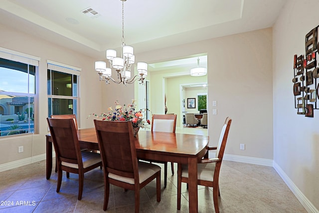 dining room featuring visible vents, baseboards, light tile patterned floors, a raised ceiling, and a chandelier