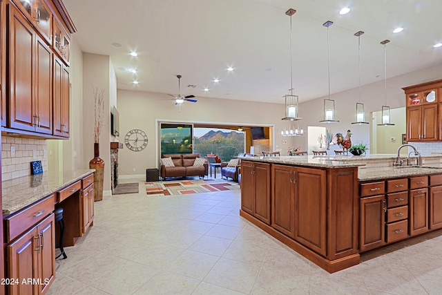 kitchen with backsplash, decorative light fixtures, open floor plan, a ceiling fan, and a sink