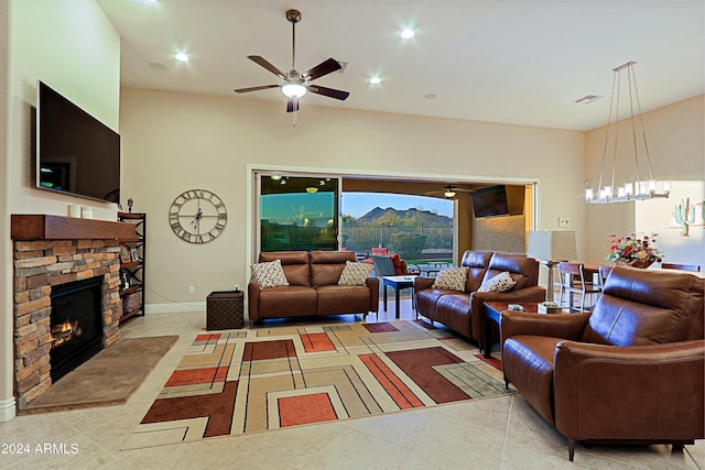 living area with tile patterned floors, recessed lighting, ceiling fan with notable chandelier, and a stone fireplace