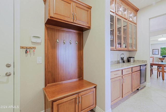 mudroom featuring wine cooler, light tile patterned floors, baseboards, and a sink