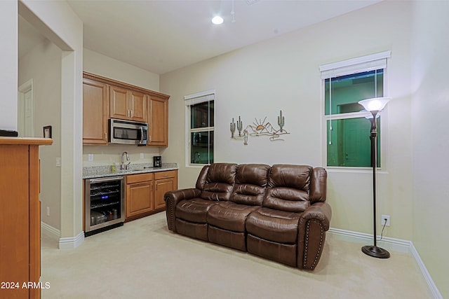 living area featuring indoor wet bar, wine cooler, baseboards, and light carpet