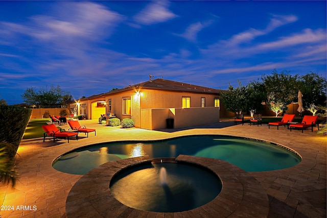 pool at dusk featuring a patio area, a pool with connected hot tub, and fence