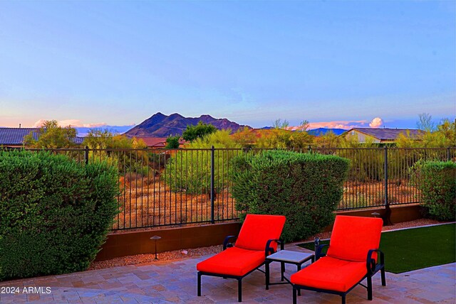 patio terrace at dusk with a mountain view and fence