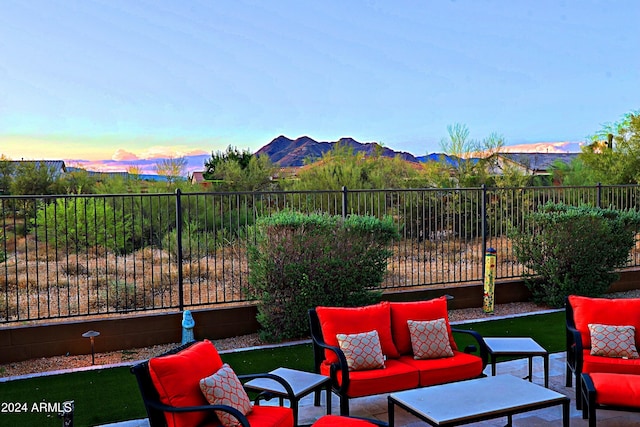 patio terrace at dusk featuring an outdoor living space, a mountain view, and fence