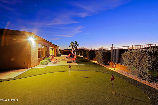 yard at dusk featuring fence and a patio area