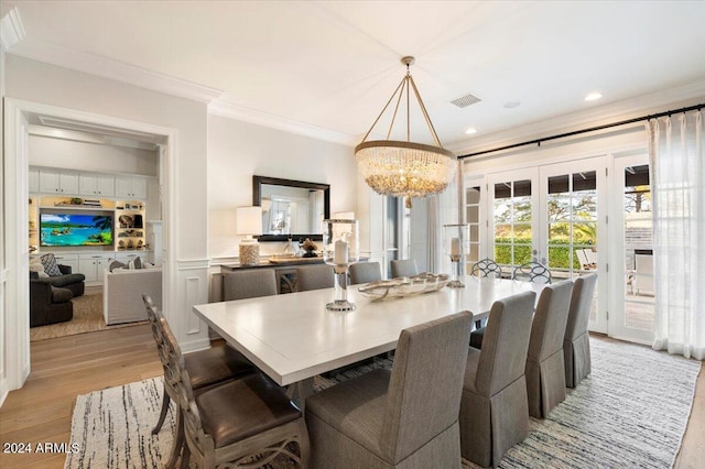 dining room featuring a notable chandelier, french doors, crown molding, and light hardwood / wood-style flooring