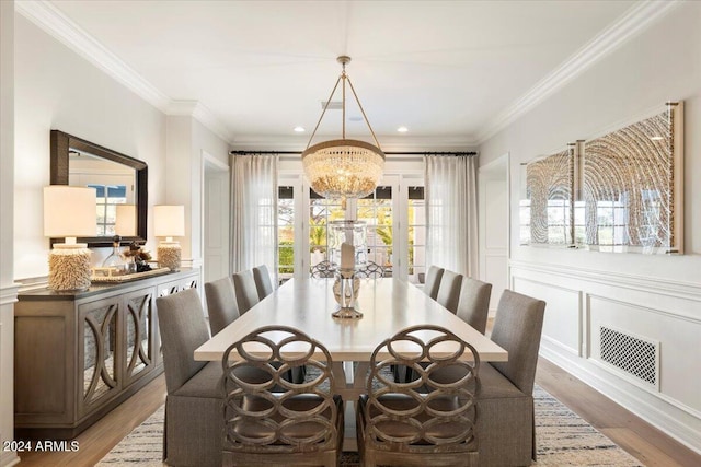 dining room with a chandelier, crown molding, and light hardwood / wood-style flooring