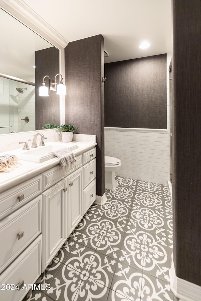 bathroom with vanity, tile patterned flooring, toilet, tile walls, and a shower with shower door