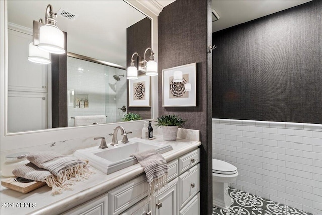 bathroom with tile patterned floors, an enclosed shower, vanity, tile walls, and toilet