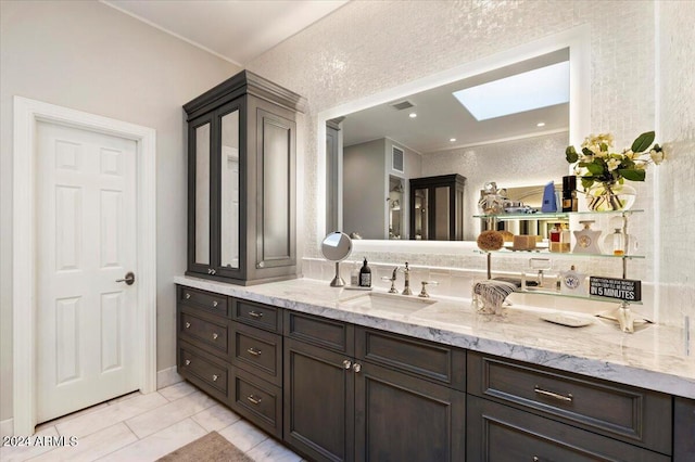 bathroom featuring vanity, a skylight, and tile patterned floors