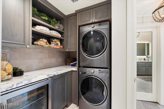 laundry room with cabinets, stacked washing maching and dryer, and wine cooler