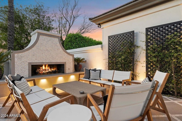 patio terrace at dusk with an outdoor living space with a fireplace