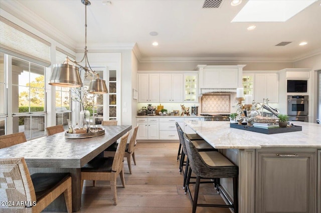 kitchen with white cabinets, a breakfast bar area, a large island, and stainless steel oven