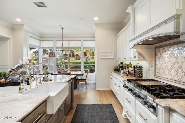 kitchen with white cabinets, custom range hood, stainless steel appliances, and decorative light fixtures