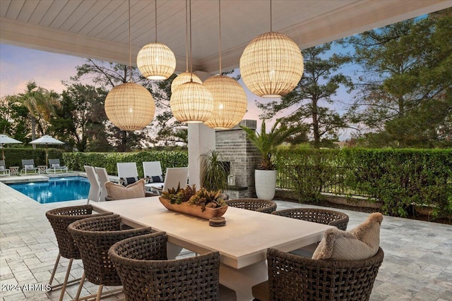 patio terrace at dusk with a fenced in pool