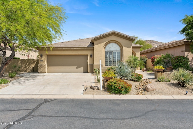view of front facade with stucco siding, an attached garage, concrete driveway, a tiled roof, and fence