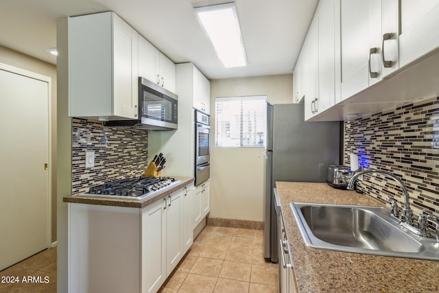 kitchen with a warming drawer, a sink, tasteful backsplash, white cabinetry, and stainless steel appliances