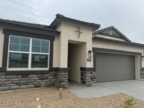 1518 S 241st Ave, Buckeye, AZ 85326 - view of front of house with stucco siding, an attached garage, concrete driveway, and stone siding