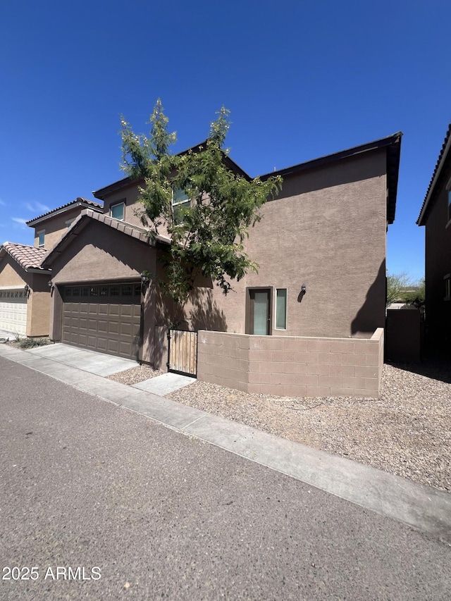 view of front of home with a gate, an attached garage, stucco siding, concrete driveway, and a fenced front yard