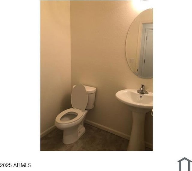 half bath featuring tile patterned flooring, toilet, and baseboards