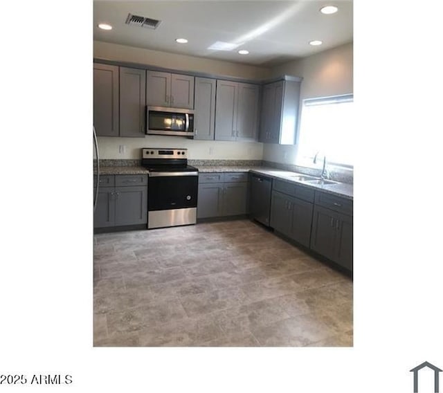 kitchen featuring visible vents, recessed lighting, a sink, gray cabinetry, and stainless steel appliances