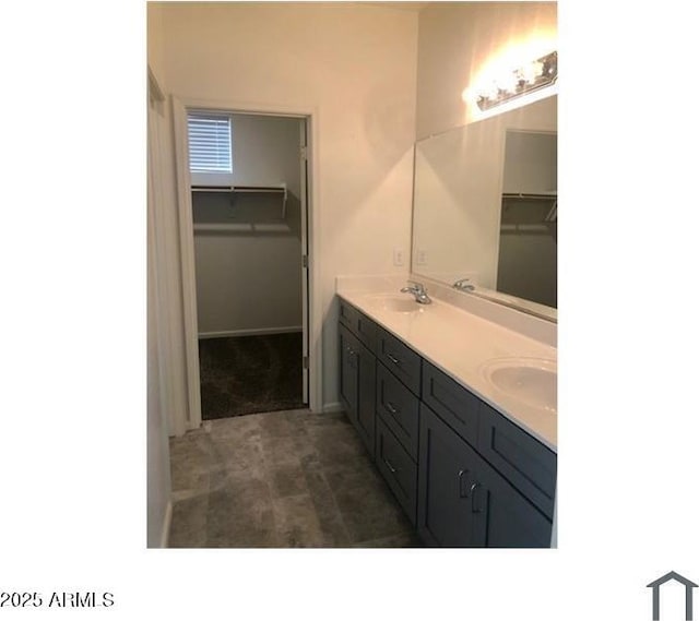 bathroom with double vanity, a spacious closet, and a sink