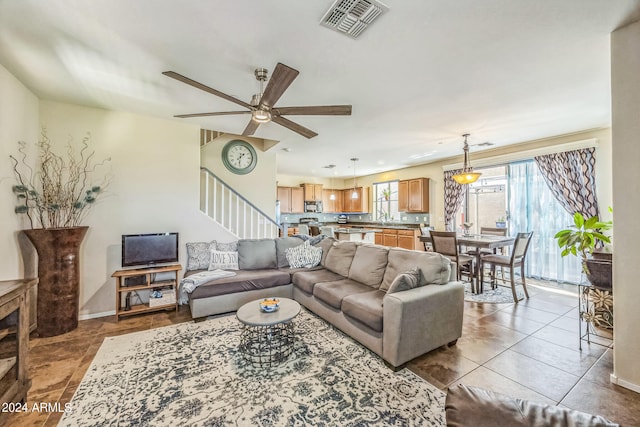 tiled living room with ceiling fan and sink