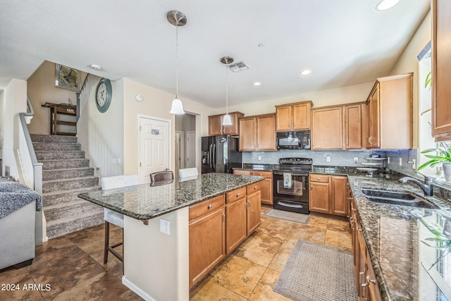 kitchen featuring black appliances, a center island, dark stone countertops, pendant lighting, and a breakfast bar area