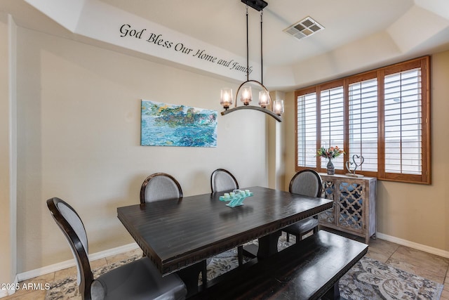 dining room featuring a tray ceiling, visible vents, and baseboards