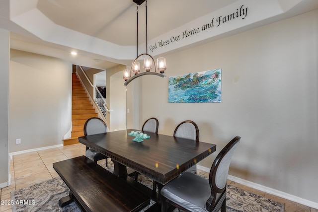 dining space with a tray ceiling, stairway, light tile patterned floors, and baseboards