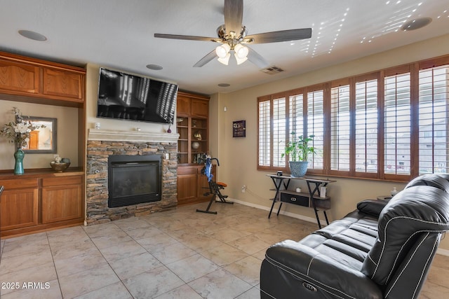 living room with visible vents, a fireplace, a ceiling fan, and baseboards